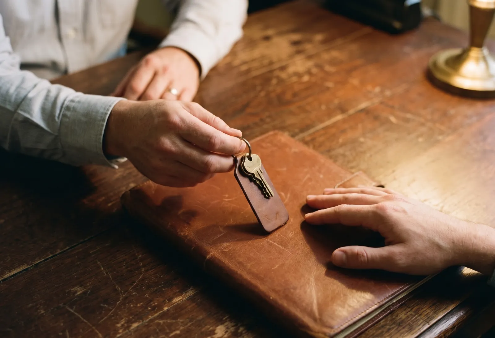 A buyer receiving a document folder and keys across a desk